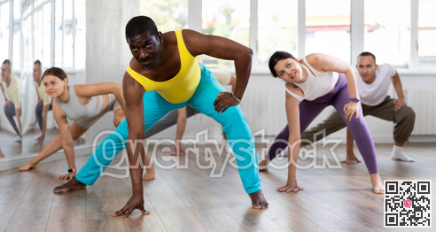 Middle-aged Afro-American man practicing aerobic dance in training hall