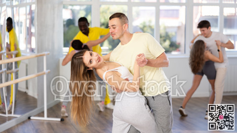 Young man and woman practicing waltz dance in pair in training hall