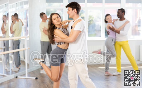 Happy pretty woman enjoying impassioned merengue with male partner in dance room during class. Social dancing concept
