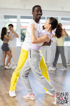 African American practicing bachata with brunette in dance class