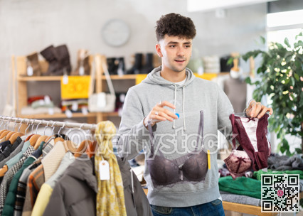 Young guy choosing bra in clothing store