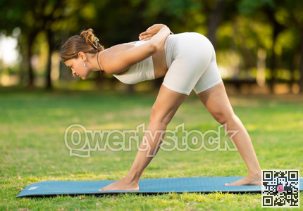Girl in park on green grass of lawn performs Parshvottanasana