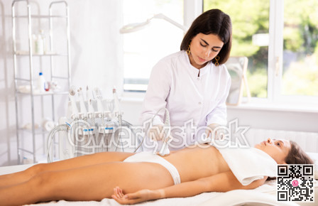 Female doctor making belly beauty massage with vibration attachement
