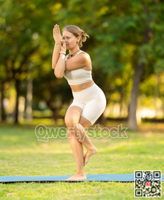 Girl enjoying outdoor yoga practice in green summer park