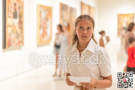 Portrait of young attractive woman holding an information booklet during a visit to fine arts museum