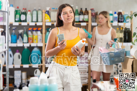 Woman consumer choose tanning product or sunscreen in household supermarket, while in background shoppers browse products