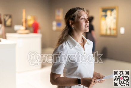 Woman with sheet piece of paper in hands view pictures and icons in museum hall
