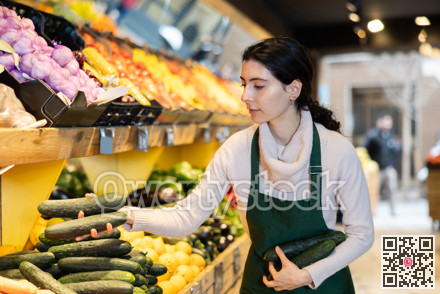 seller puts cucumbers on a shelf in a store