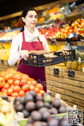 Young woman seller offering cassava in vegetable shop