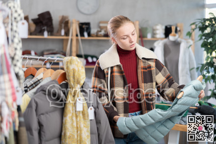 While shopping, teen girl browsing goods items and choose elect down vest in store