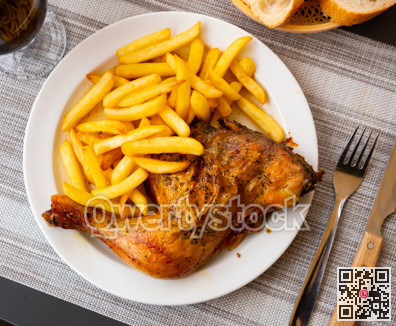 Chilindron chicken thighs with baked potatoes on a ceramic plate cooked in cafe