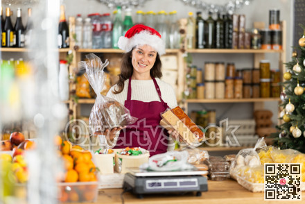 Woman works as salesperson, waiting for customers at store counter, New Year Eve