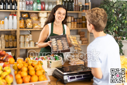 Female seller offers to buy cookies to teenage boy in interior of grocery supermarket