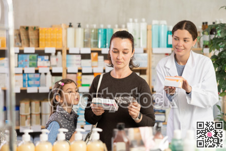 Woman with daughter choosing box of medicine with pharmacist assistance in pharmacy