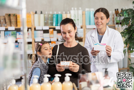 Woman with daughter choosing box of medicine with pharmacist assistance in pharmacy