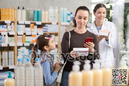 Middle-aged woman with daughter scanning barcode on pills in drugstore