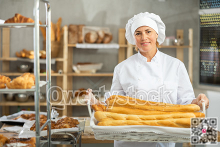 Adult female baker with basket of baguettes
