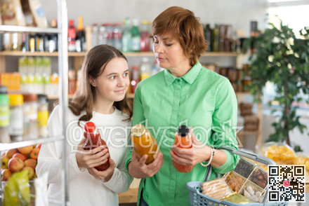 Mother and daughter choose tasty juice together in grocery section of supermarket