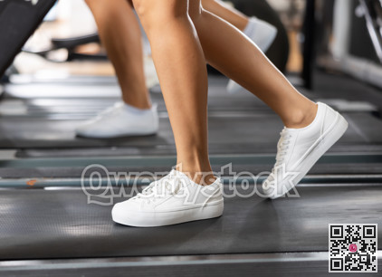 Feet of young girl walk on treadmill in gym