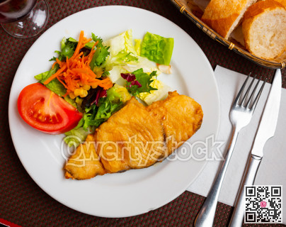 On plate there is small portion of salad of fresh vegetables and piece of fried fillet of white fish