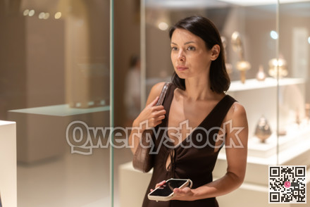 Young female visitor stands near glass display case in museum