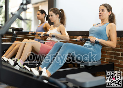 Sportive young girls training on cable row machine in gym