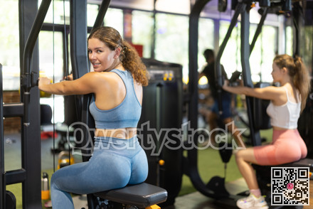Positive young girl training on chest fly machine in gym
