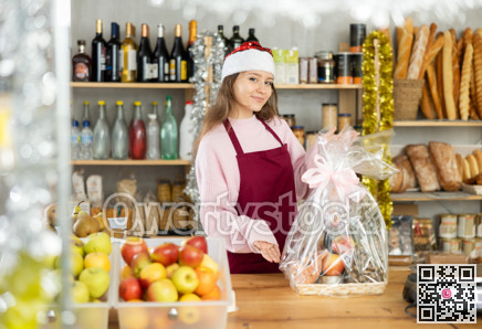 Young saleswoman is holding New Year package of products in grocery store