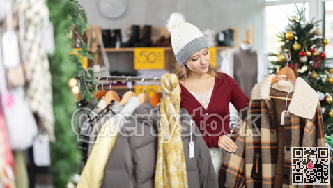Young woman choosing coats and jackets at Christmas sale