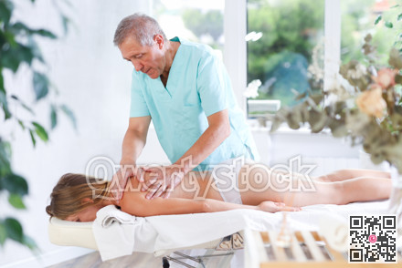 Skilled old masseur conducting back massage for woman client