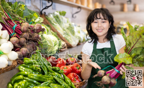 Smiling young saleswoman holding beetroots in grocery store