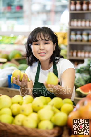 Young asian salesgirl laying out fresh pears on produce display