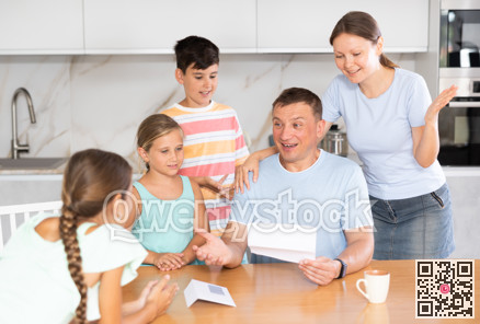 Joyful father of family with children and wife read letter in kitchen.