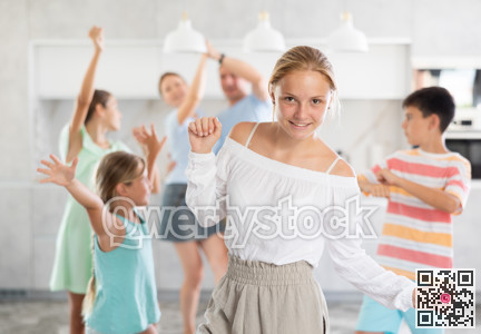Behind cheerful girl, big family of parents, sisters, brother is rejoicing, dancing, having fun.