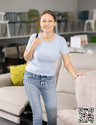 Positive woman chooses modern sofa in furniture store