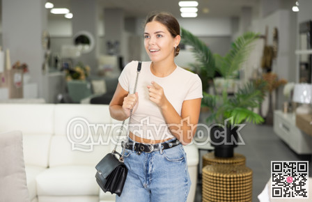 Positive young woman choosing new upholstered furniture in furniture store