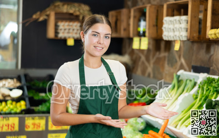 Positive and friendly store girl employee stands with arms crossed on chest and waits for customers