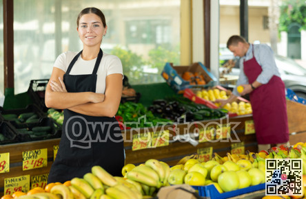 Positive and friendly store girl employee stands with arms crossed on chest and waits for customers