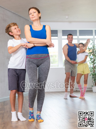 Happy mother and son practicing dance in pairs together with other family members