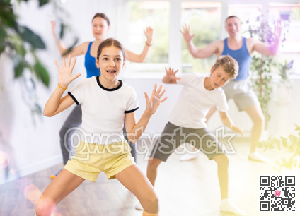 Parents together with their children learn how to dance salsa or boogie-woogie in dance class