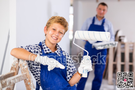 Portrait of positive young boy with paint roller