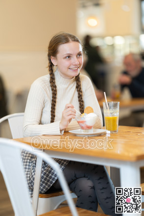 Food court teen girl visitor sits near table, eating ice cream in chain cafe shop