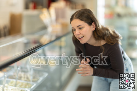 Young woman is choosing with interest what flavor of ice cream to try