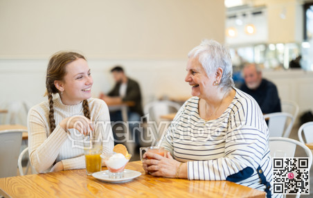 Grandmother and teenage girl sitting at table in cafe.