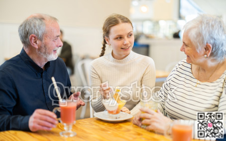 Grandparents and teenage girl sitting at table in cafe.