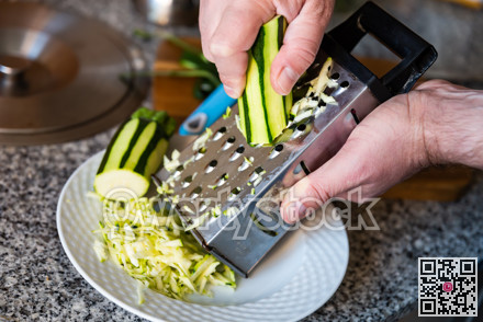 Mens hands hold piece of ripe zucchini and chop vegetables with grater