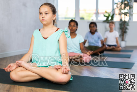 Training yoga kids on yoga mat in gym.