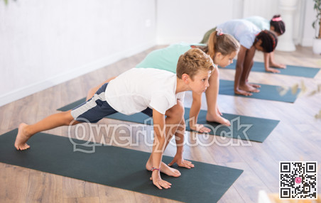 Multiethnic preteen children in dog pose exercising during yoga class in studio