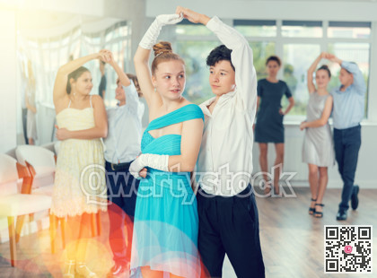 Smiling girls paired with guys dance salsa in dance class