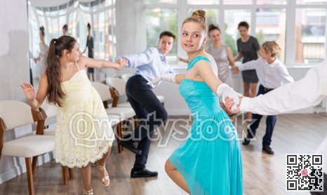 Cheerful teenage girl dancing jive with partner in choreography studio